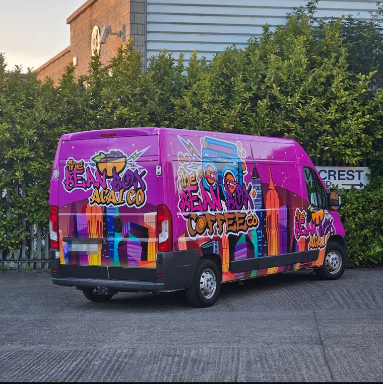 The Bean Box van, wrapped top to bottom in graffiti art — the boombox logo, a New York City skyline and the Açaí Co tag, in pink, purple and orange.